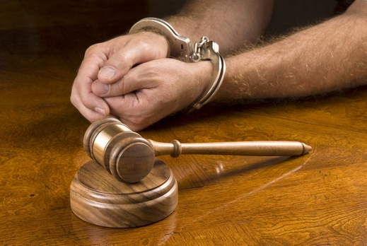 A man arrested awaits the judge to use his gavel to render a decision.